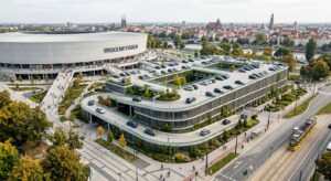 A high-angle architectural visualization of a modern multi-level parking structure integrated into t