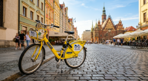 A high-quality, editorial-style photograph of a recognizable yellow Wrocław city bike parked on a cl